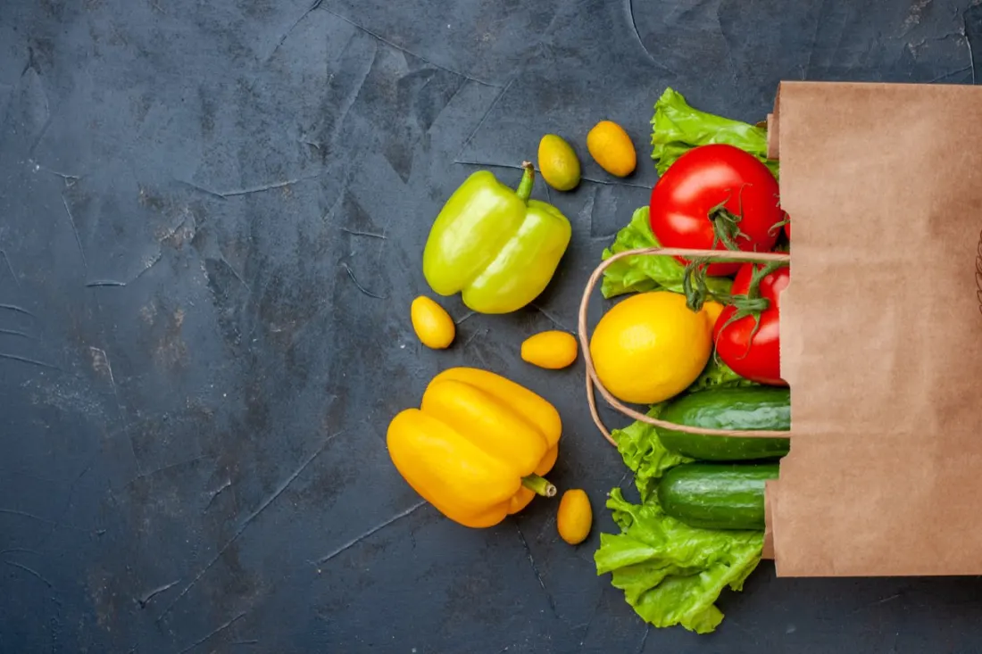 Fresh vegetables in a paper grocery bag for blood-pressure-friendly food choices.