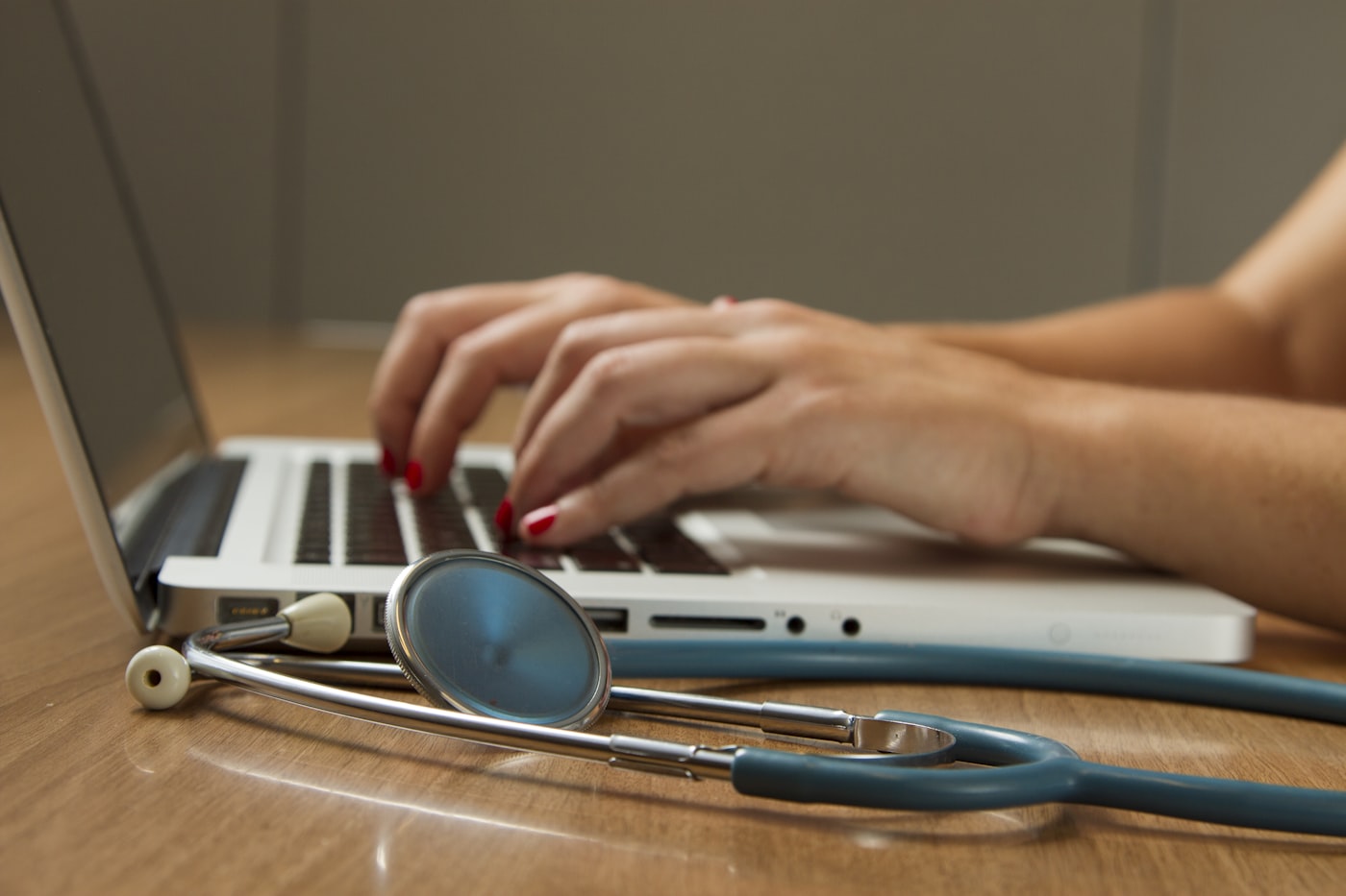 Stethoscope beside a laptop on a clinician workspace.
